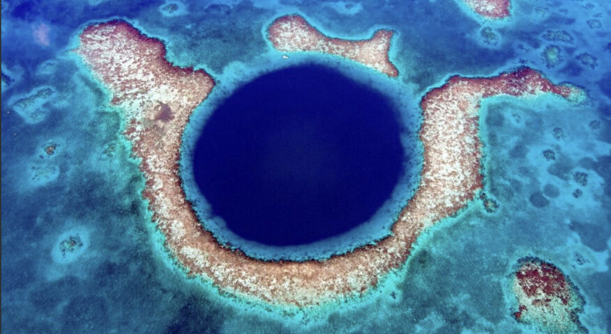 dark blue hole amid islands in shallow ocean